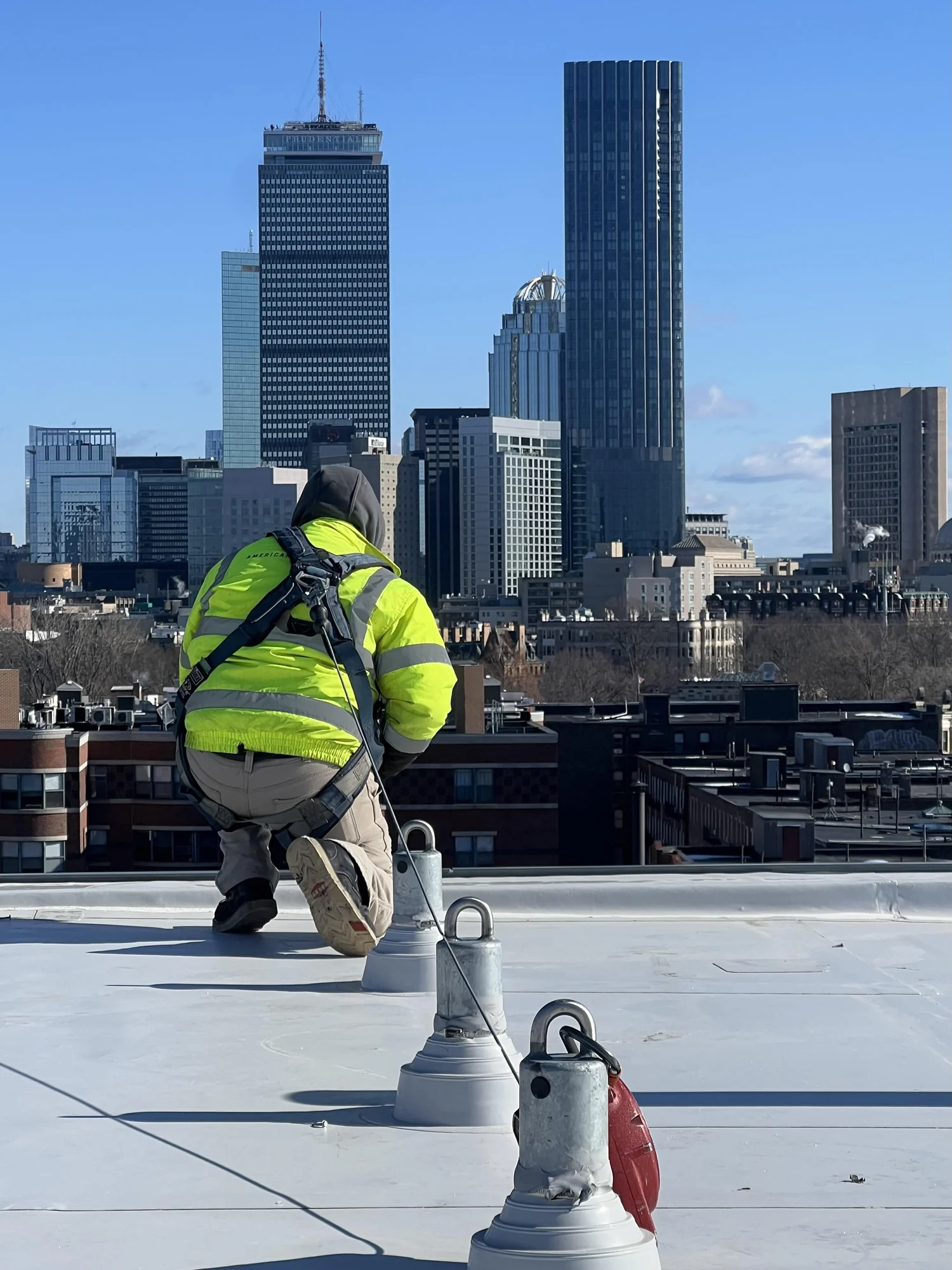 Technician tethered to rooftop anchors above Boston
