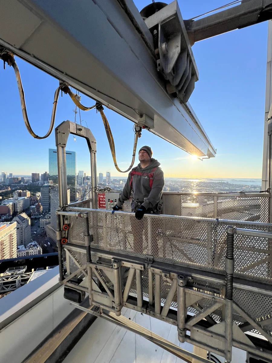 Technician in a suspended building maintenance platform
