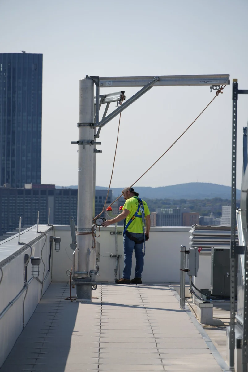 American Anchor specialist beside a rooftop davit system
