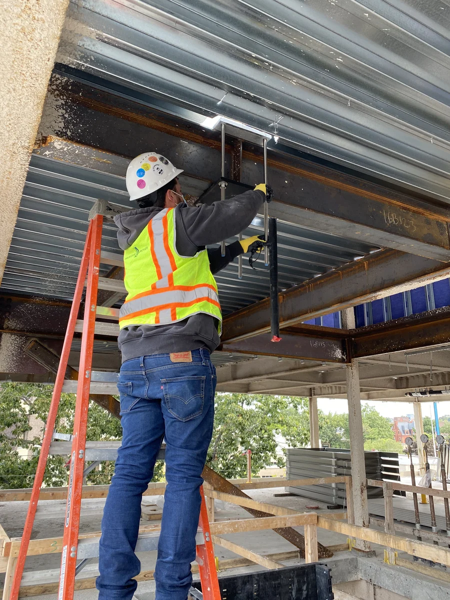 Technician fastening an anchor around a steel beam