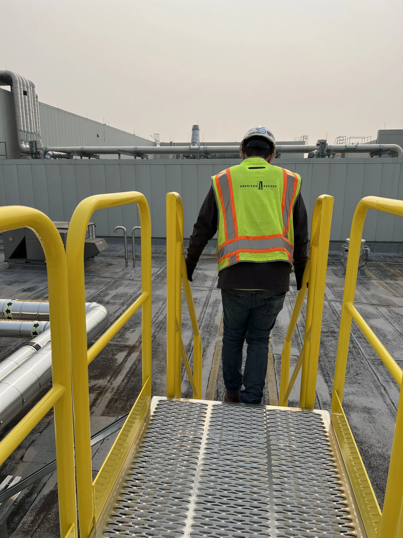 Installed grated roof access platform and yellow rails.