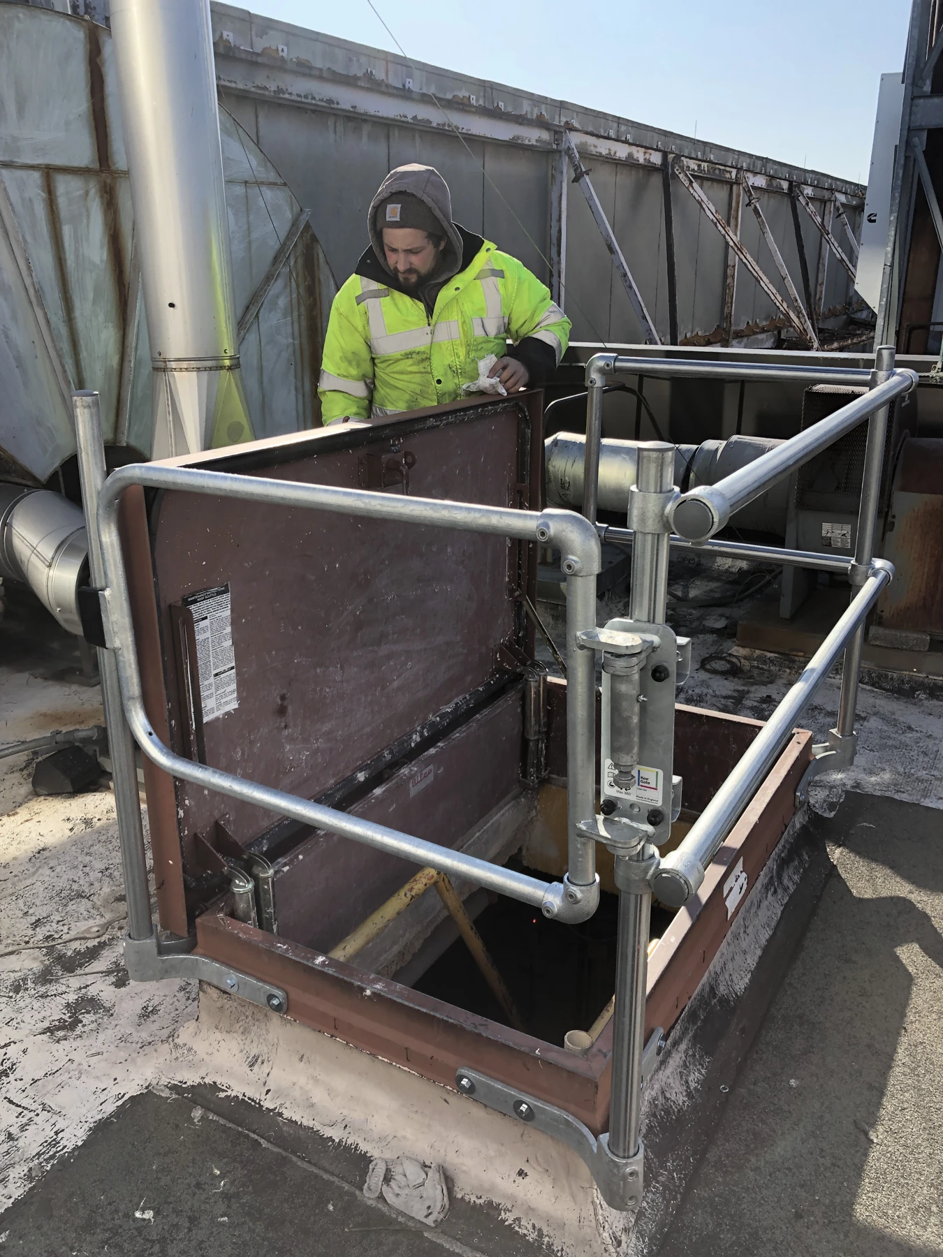 Roof hatch guard installation with a worker.