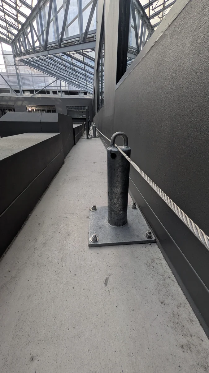 Installed lifeline and support anchor beside an elevated route.